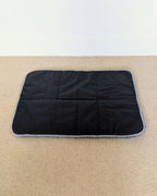 Bottom view of the wool mat with black anti slip fabric, and black and white strip binding. 