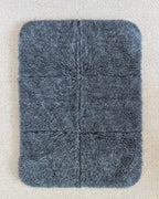 Flat lay, top view of grey wool mat on beige carpet. 
